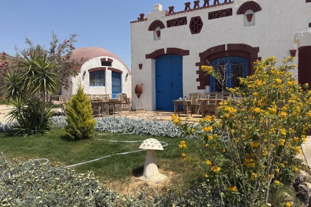 A building with a white facade, blue doors, and a dome structure.