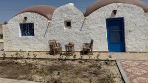 Un edificio con un diseño arquitectónico singular, con una serie de estructuras abovedadas y un frente texturizado y una puerta azul.