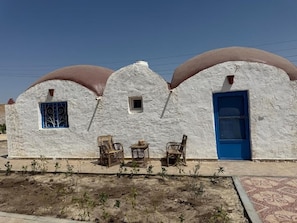 A building with a unique architectural design, featuring a series of arched structures with a textured facade and a blue door. - VILLA EL SAFIR FARMHOUSE (Beheira Governorate)