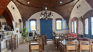 Una habitación con techo abovedado, un candelabro central y una puerta azul.