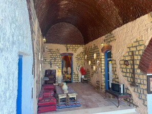 Una habitación con techo abovedado, paredes de piedra, un conjunto de sofás, un televisor y una pequeña mesa.