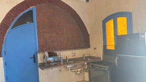 Una cocina con una puerta azul, un horno de ladrillo y un refrigerador negro.