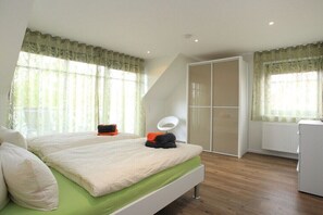 A bedroom with a bed, a wardrobe, a radiator, and a window with curtains. - Holiday apartment with 3 bedrooms (Borkum)