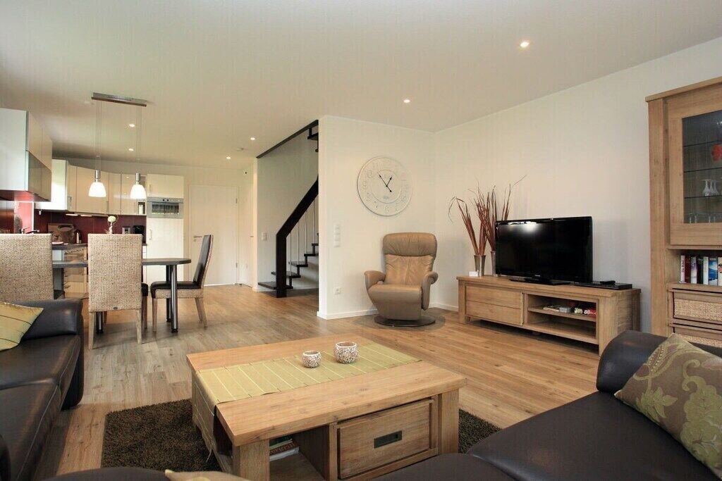 Un salon moderne comprenant un canapé, une table basse, un meuble pour la télévision et un coin repas avec des chaises et une table.