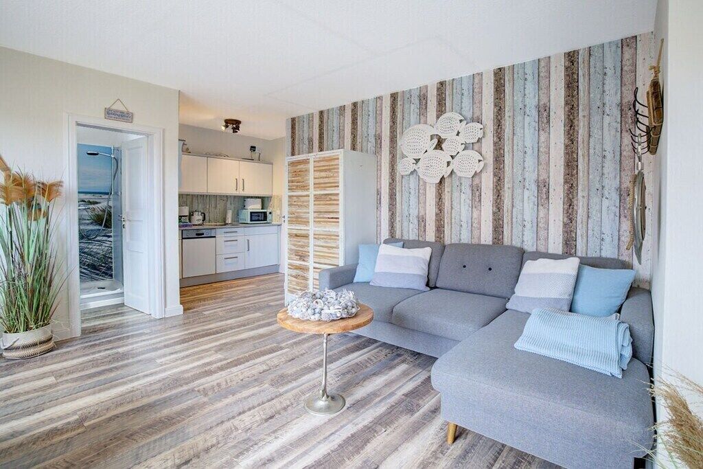 Ein modernes Wohnzimmer mit einem grauen Sofa, einem kleinen Holztisch und einer gestreiften Wand.