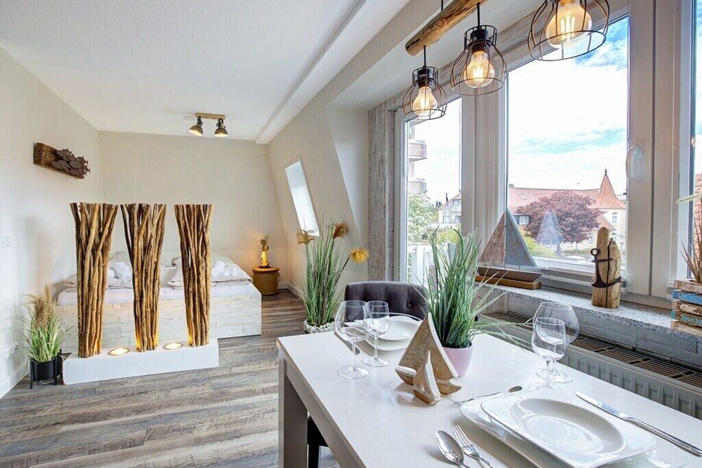A dining area with a white table set for two, a view of the outside, and a modern interior design.