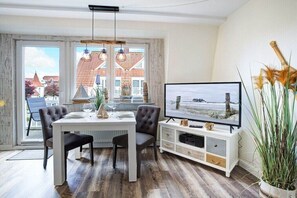 A dining area with a table, chairs, and a television. - Villa by the sea, home port (Sankt Peter-Ording)