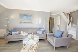 A modern living room with a grey sofa set, a coffee table, and a painting on the wall. - Holiday apartment with 2 bedrooms (Sankt Peter-Ording)