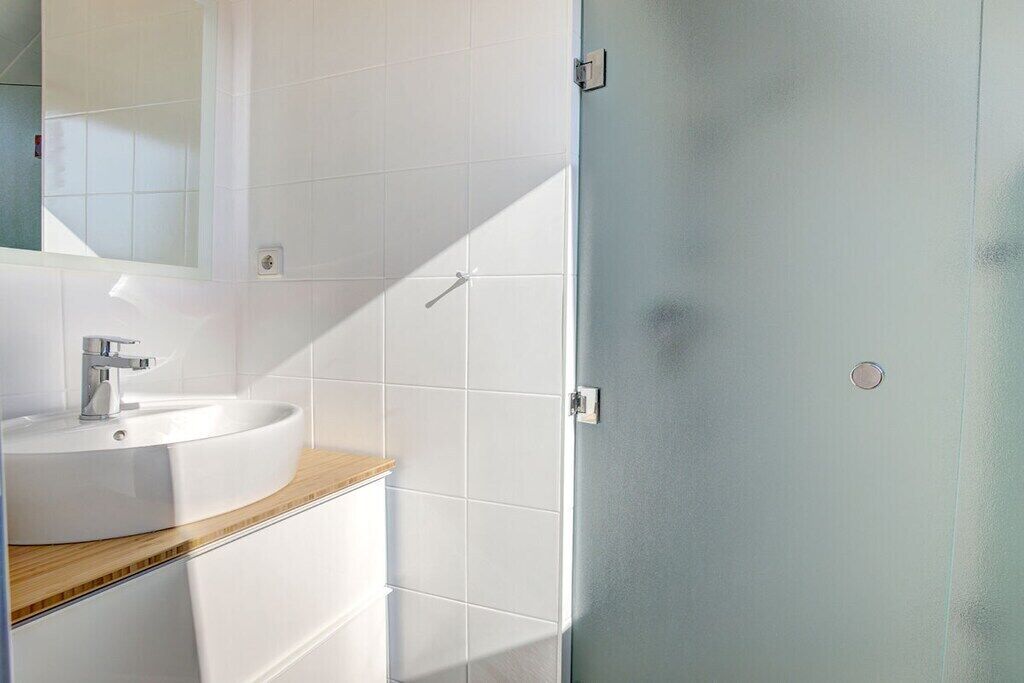 Ein Badezimmer mit einem weißen Waschbecken, einem Spiegel und einer Tür.
