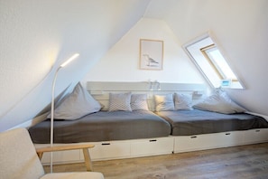 Een moderne loft slaapkamer met een schuine kap, een ingebouwde bank met opbergladen, een lijstwerk kunstwerk van een vogel en een dakraam.