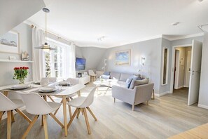 A modern living room with a dining area, a sofa, and a television. - Holiday apartment with 2 bedrooms (Sankt Peter-Ording)