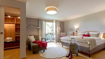 A hotel room with a bed, a seating area, a suitcase, and a view of the outdoors.