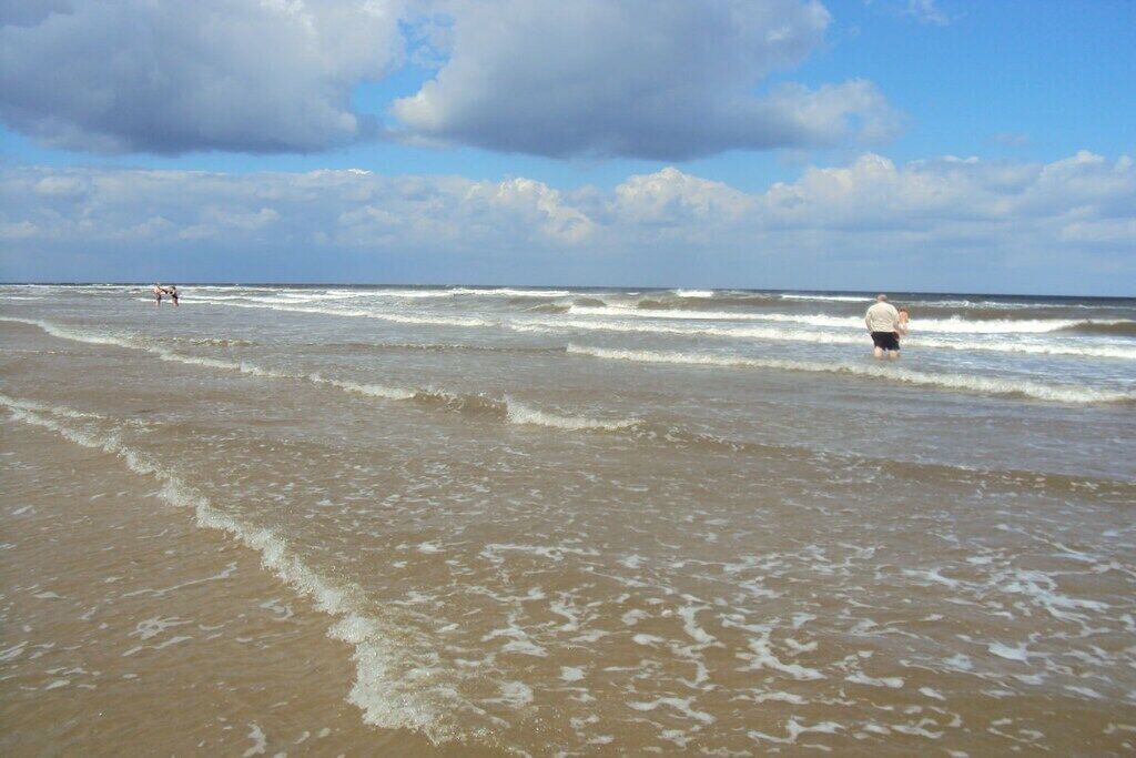 A beach with waves and a person standing in the water.