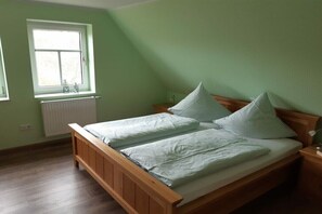 Un dormitorio con cama de madera, ventana con radiador y pared verde.
