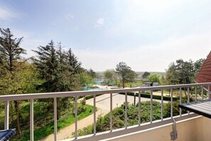 A balcony with a view of a green landscape, a pathway, and a distant building. - Holiday home with 1 bedroom (St. Peter-Ording)