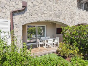 Ein Steinhaus mit einer Terrasse, auf der ein Tisch und Stühle stehen.