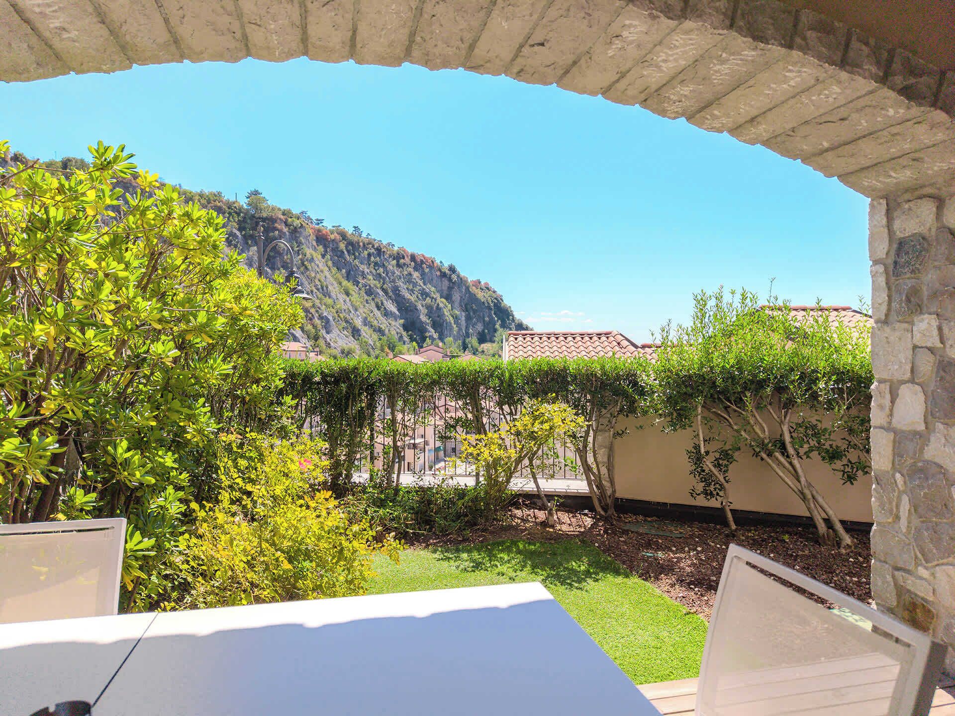 Une cour offrant une vue sur une montagne, agrémentée d’une pergola et d’un mur en pierre.