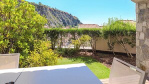 Een binnentuin met uitzicht op een berg, een pergola en een stenen muur.