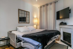 Une chambre à coucher moderne avec un lit, une table de chevet, une lampe, une télévision et une cheminée.