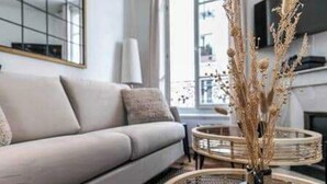 Ein modernes Wohnzimmer mit einer Couch, einem runden Couchtisch und einer dekorativen Vase mit Trockenpflanzen.