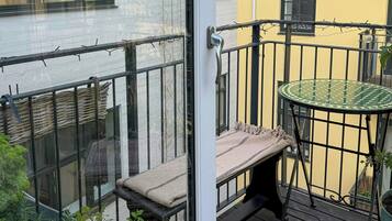 Un balcone con una porta vetrata, un tavolino rotondo, una panca e piante in vaso.