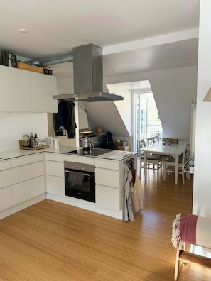 A modern kitchen with white cabinetry, a built-in oven, and a large island. - Rooftop flat near Gammel Strand and Tivoli (København K)
