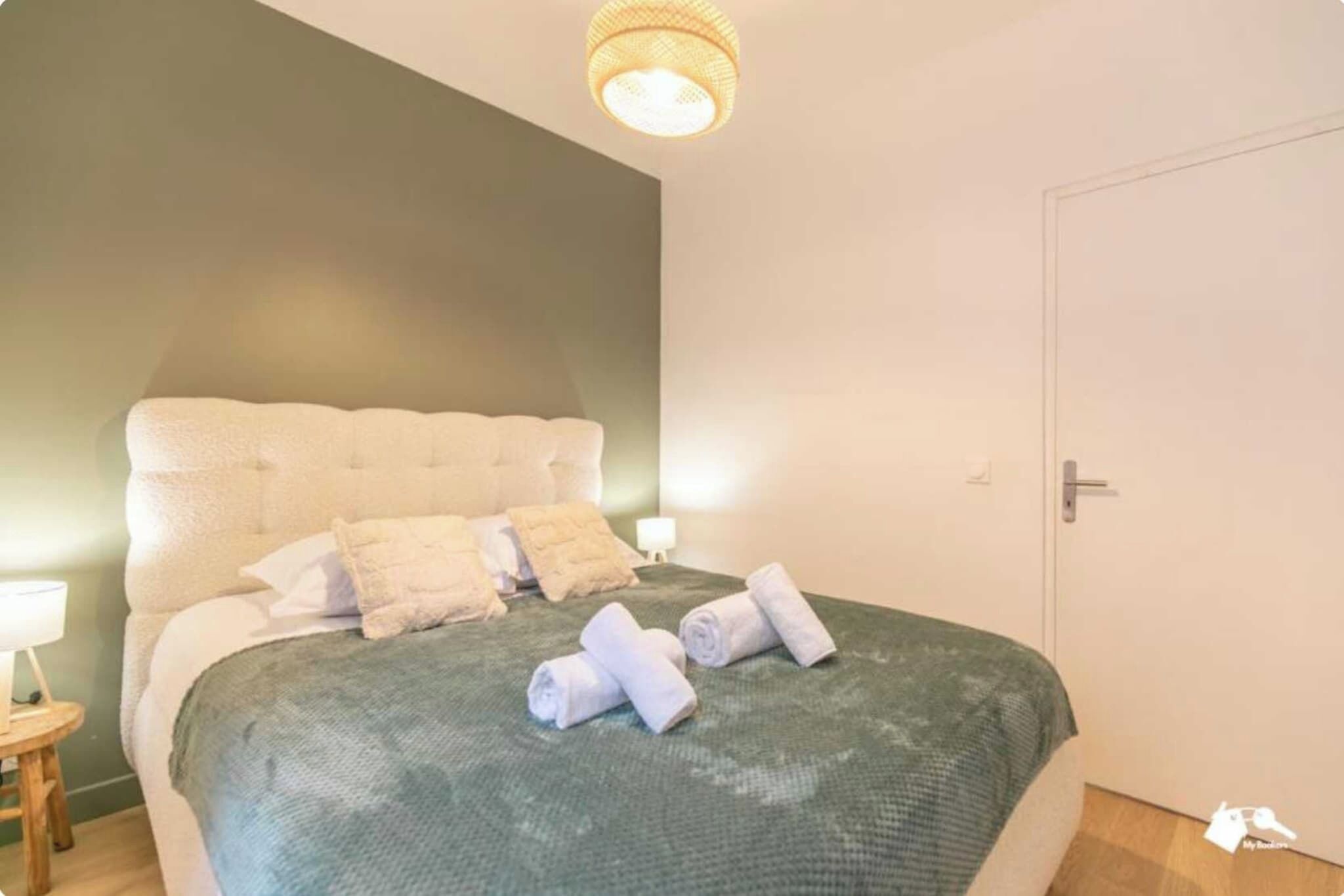 Une chambre à coucher avec un lit, des oreillers, une table de chevet avec une lampe et une porte.