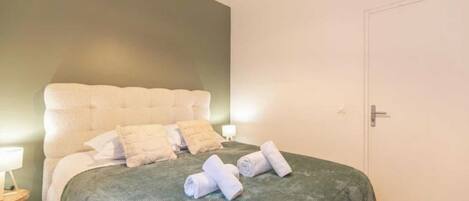 Une chambre à coucher avec un lit, des oreillers, une table de chevet avec une lampe et une porte.