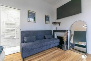 Ein modernes Wohnzimmer mit einem grauen Sofa, Holzböden, einem Kamin und einem großen Spiegel.