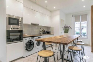 Une cuisine moderne dotée d’appareils électroménagers intégrés, d’un bar en bois et de tabourets de bar.