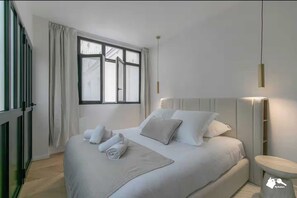 A modern hotel room with a large bed, a bedside table, a nightstand, and a window with curtains. - Stunning Apartment  - 4BR/8P - Gare de l'Est (Paris)