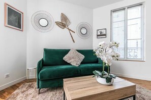 A living room with a green sofa, a wooden coffee table, and a potted orchid. - Charming apartment - 2BR/6P - Montreuil near Paris (Montreuil)