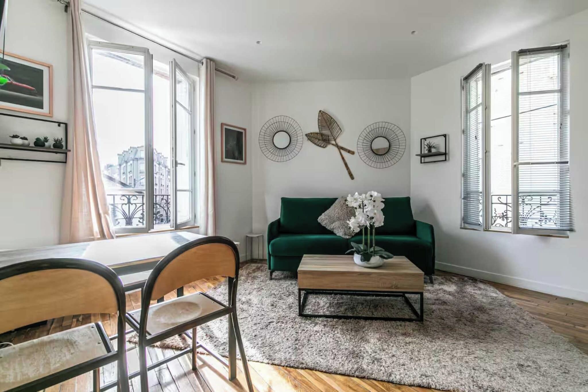 A living room with a green sofa, a coffee table, and a dining area with chairs.
