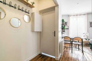 Una habitación con piso de madera, una puerta blanca, un área de comedor con sillas y una mesa, y espejos fijados a la pared.