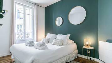 Une chambre à coucher avec un lit, deux miroirs placés sur les tables de chevet, une lampe de chevet et une vue sur l’extérieur.