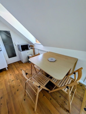 Une petite cuisine compacte avec une table et des chaises en bois, un four à micro-ondes et un petit placard.