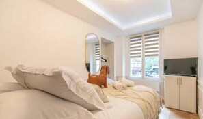 A bedroom with a bed, a TV, a wardrobe, and a window with shutters. - Luxury 1BDR/4P Apartment in the heart of Paris (Paris)
