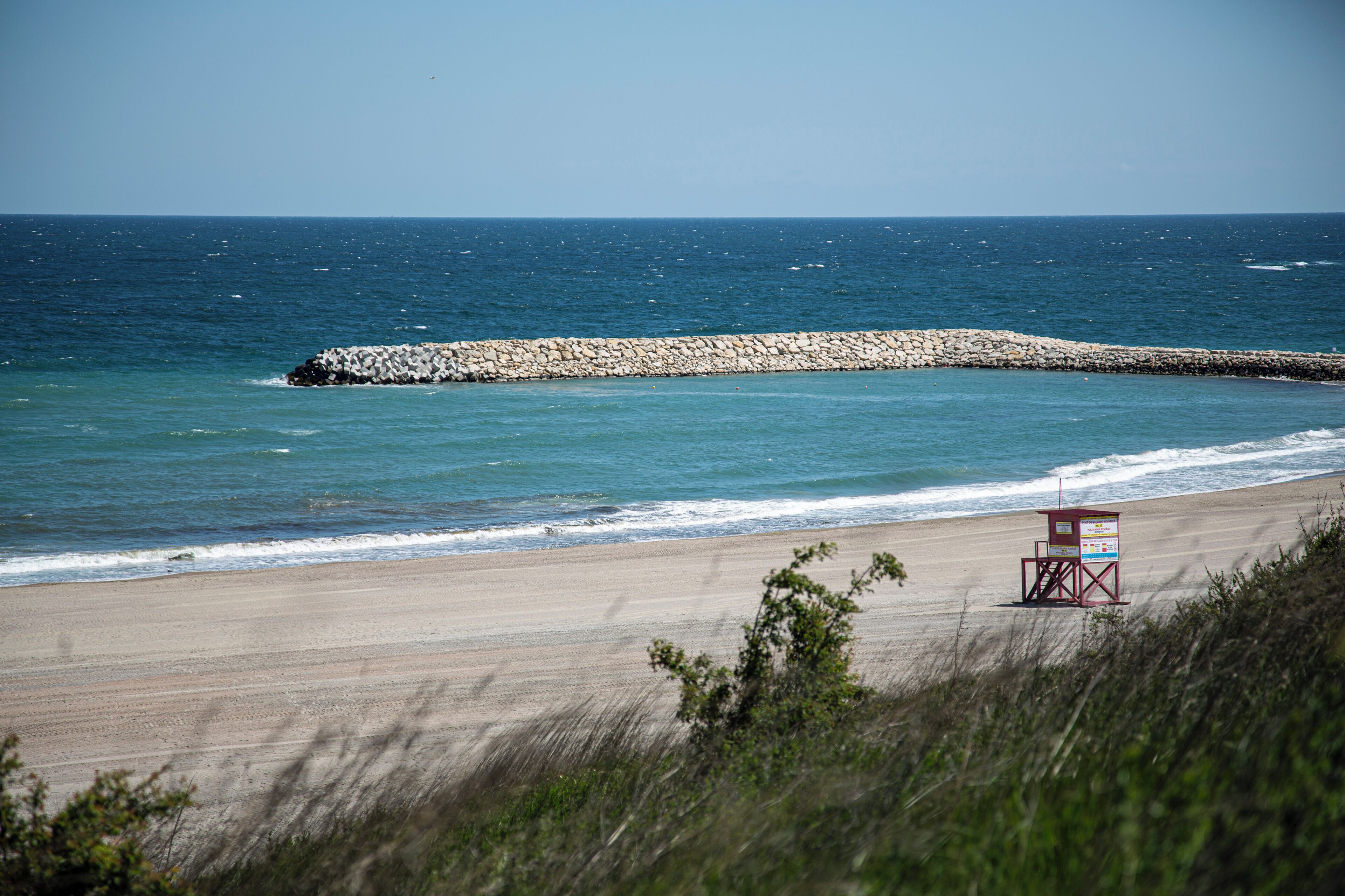 Una playa con una torre de salvavidas y un rompeolas rocoso.