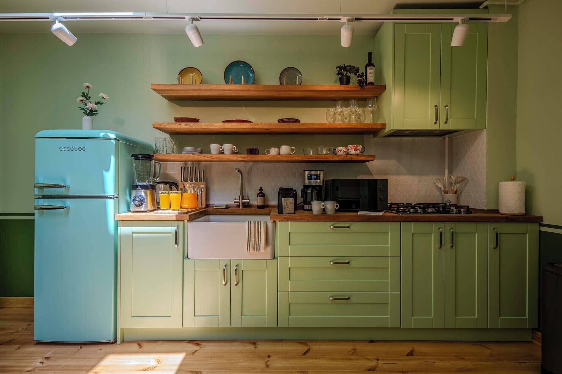 Une cuisine avec un réfrigérateur ancien, des étagères en bois et une cuisinière à gaz.
