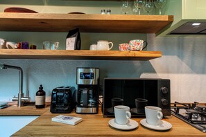 Una cocina con cafetera, microondas, tostadora y estufa a gas.
