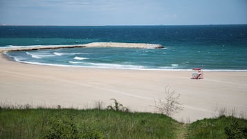 A beach with a lifeguard tower, a rocky breakwater, and a clear sky.