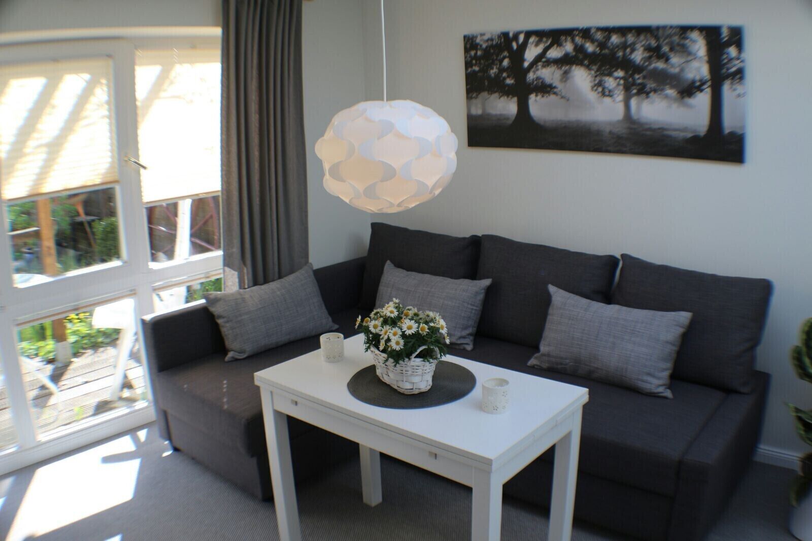 Un salon moderne avec un canapé gris, une table basse blanche et un luminaire suspendu.