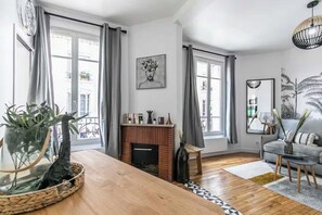 Un salon moderne avec une cheminée, de grandes fenêtres et un canapé gris.