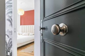 A room with a bed, a red wall, and a door with a round knob. - Apartment Modern - 2BR/6P - Montreuil- Near Paris (Montreuil)