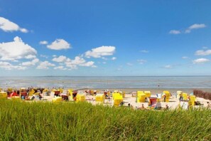 A beach with rows of yellow beach chairs and umbrellas, a clear sky, and the sea in the background. - 7 in Villa Meeresblau (Cuxhaven)