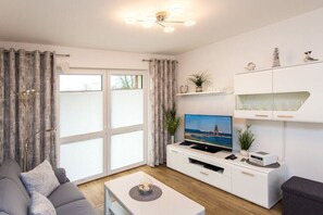 A modern living room with a sofa, coffee table, TV, and white cabinetry. - 7 in Villa Meeresblau (Cuxhaven)