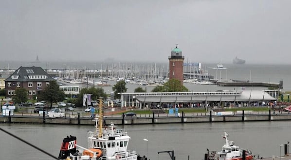 A harbor with boats, a lighthouse, and a building with a green roof. - 7 in Villa Meeresblau (Cuxhaven)
