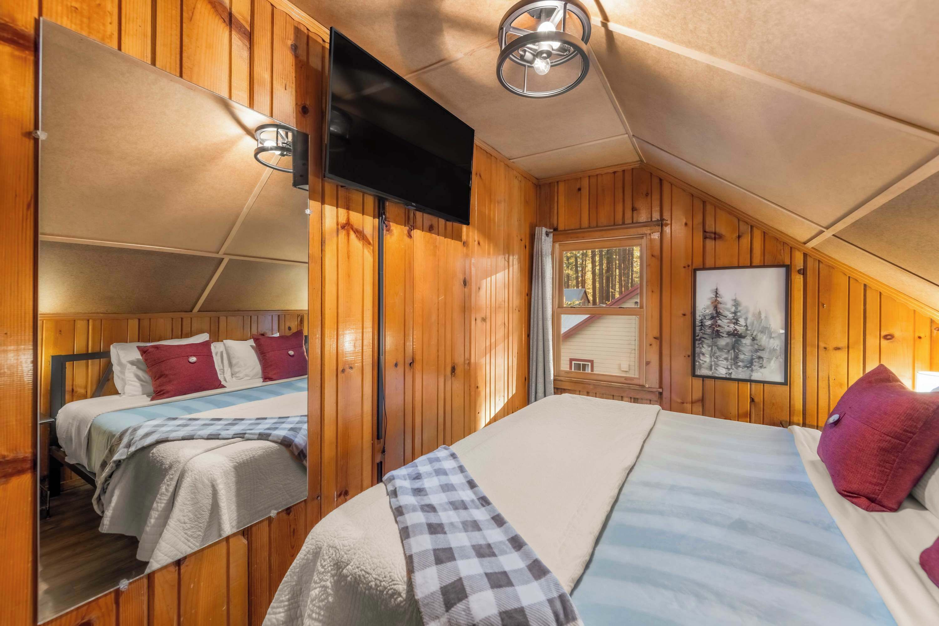 Ein gemütliches Schlafzimmer in einer Holzhütte mit einem großen Bett, einem Spiegel und einem Fernseher.