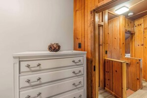 A white dresser with multiple drawers and a decorative item on top, situated in a hallway with wooden paneling and a door leading to another room. - Bearfoot Cabin - Central Tahoe Cabin (South Lake Tahoe)