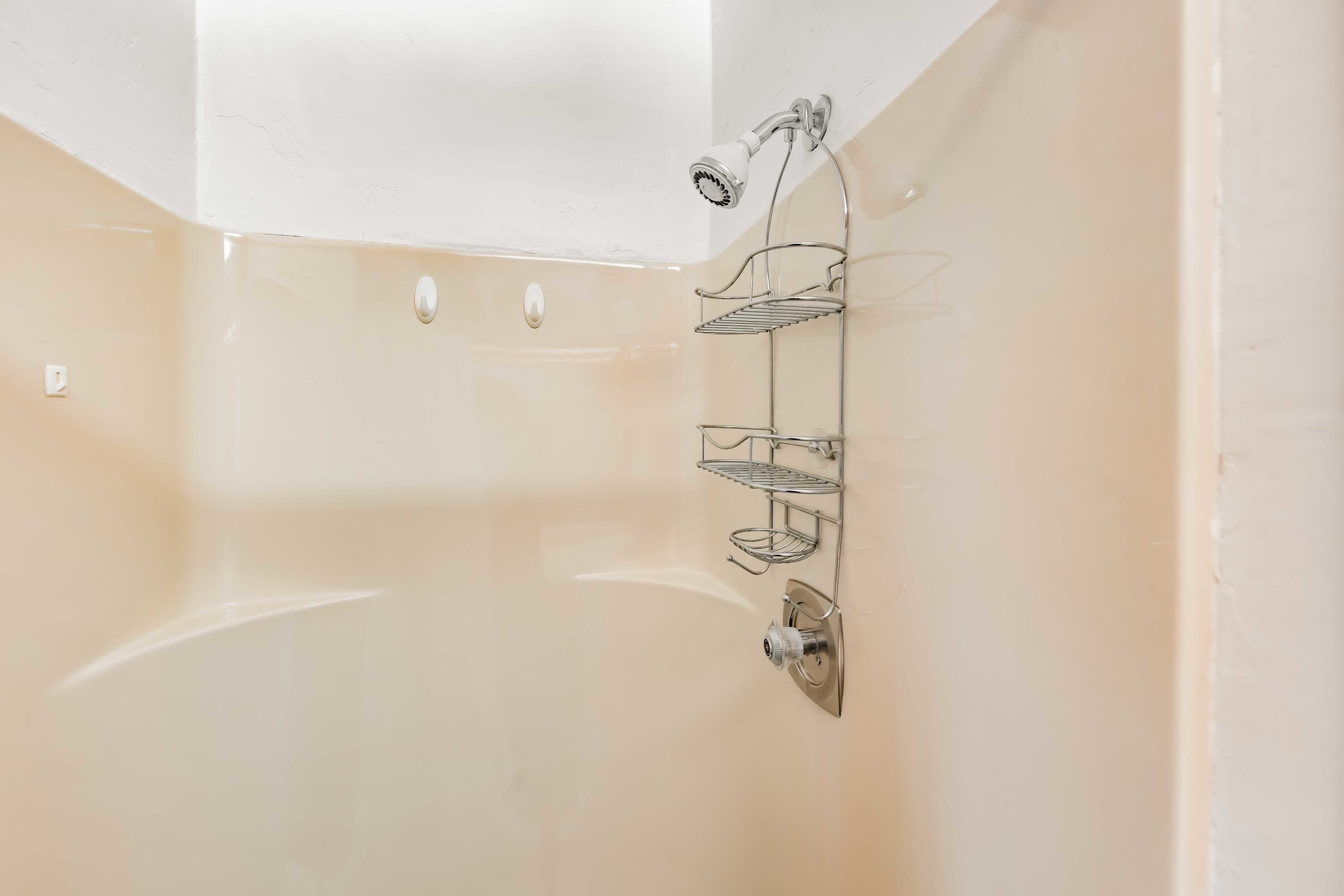Ein Badezimmer mit einer Badewanne, einer Duschbrause und einem Metallregal.